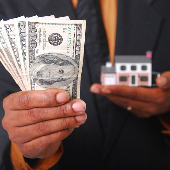 Man Holding a Miniature House and US Currency