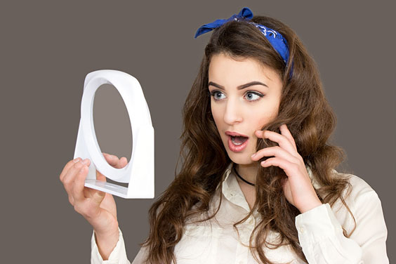 Woman Looks at her Face in a Mirror