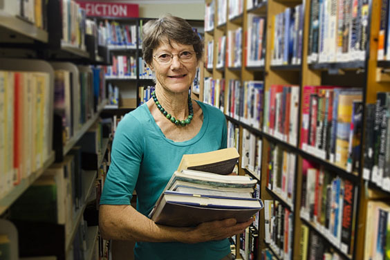 Librarian Standing between Bookshelves in a Library