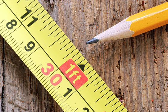 Tape Measure and Pencil on a Wooden Board