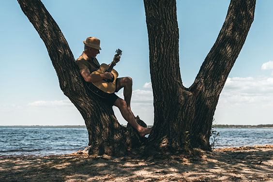 Senior Man Strumming his Guitar at the Beach